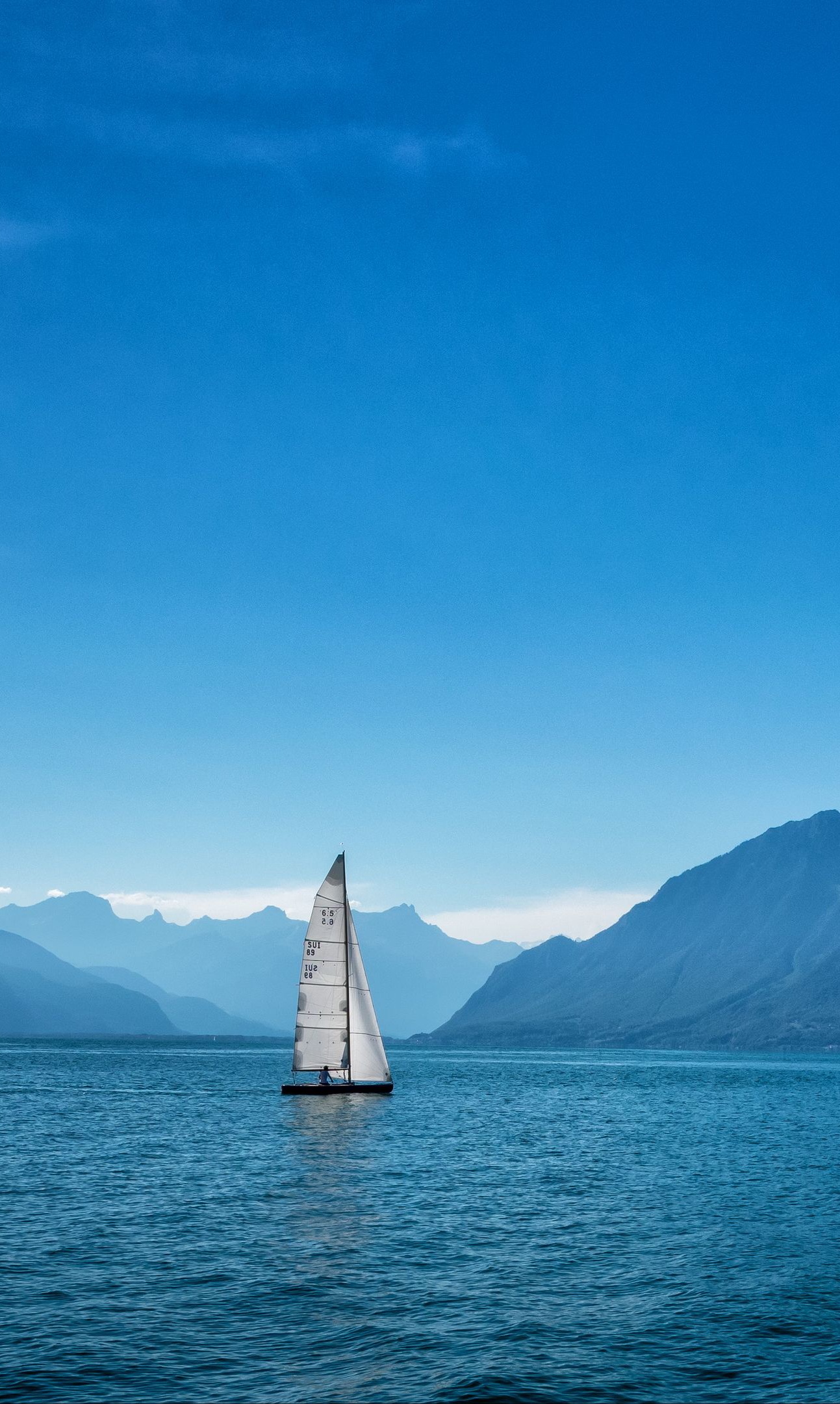 sailboat lake mountains blue serene